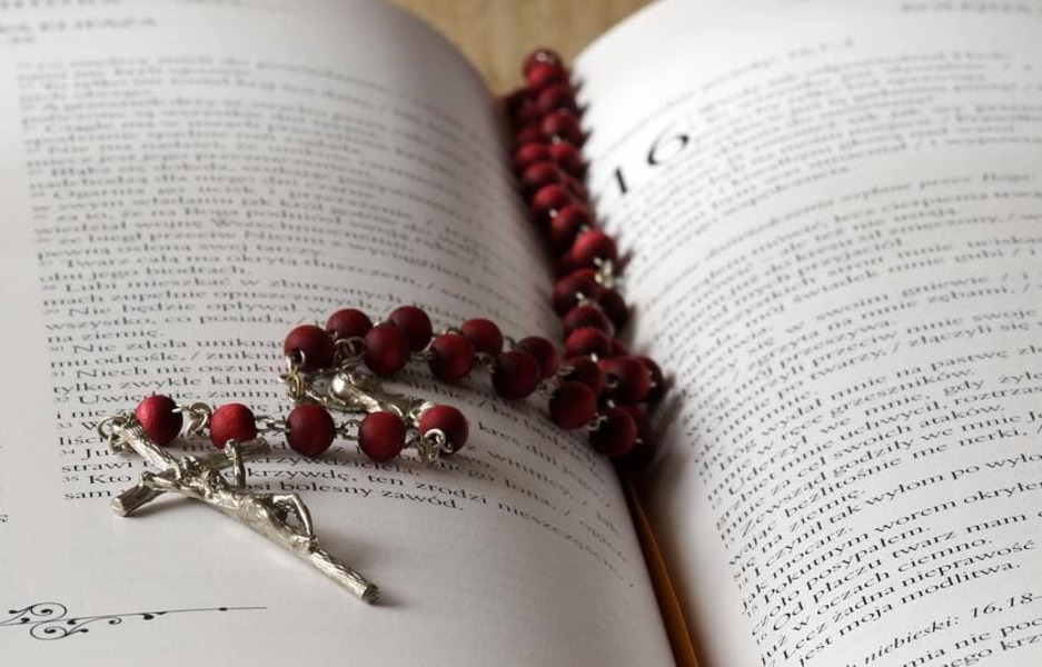 A picture of the Bible with a set of rosary beads