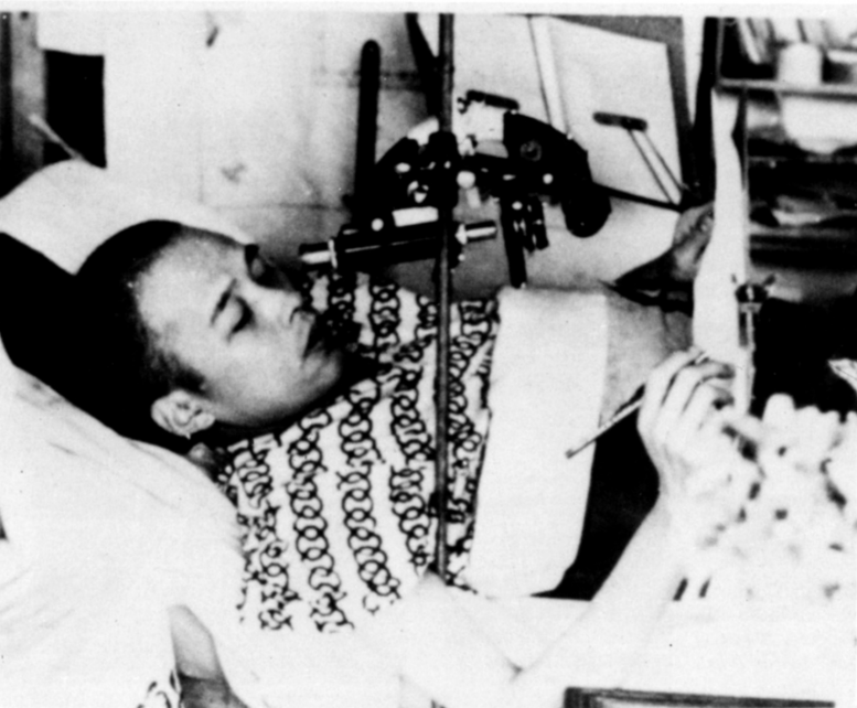 A bedridden Takashi Nagai looking at a microscope
